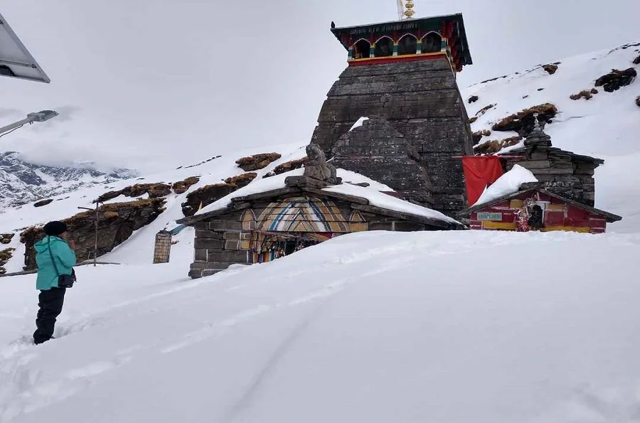 View of Tungnath temple completely covered in Snow with a devotee praying to the diety